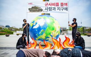 불타는 지구 모형 앞에 사람들이 쓰러져 있다.